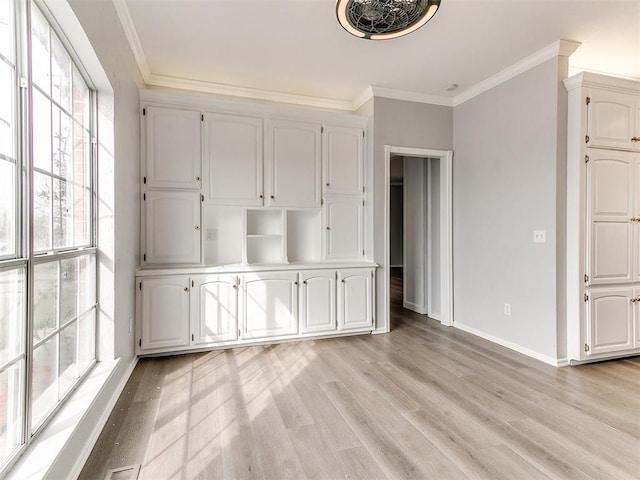 interior space featuring light wood-type flooring, baseboards, and crown molding