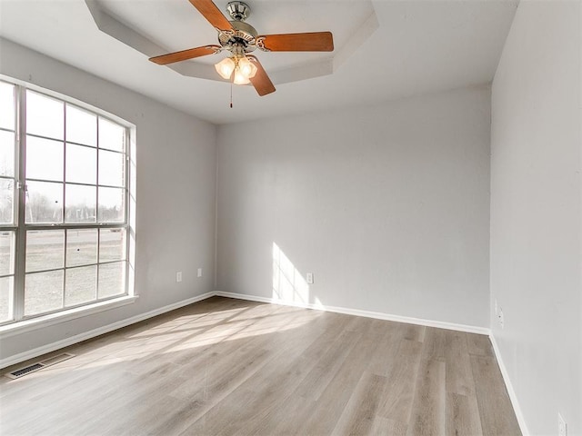 spare room with ceiling fan, visible vents, baseboards, and wood finished floors