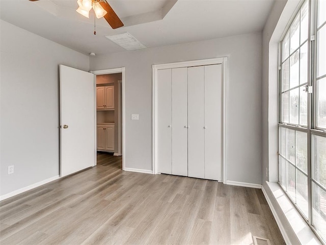 unfurnished bedroom featuring visible vents, light wood-type flooring, a closet, and baseboards