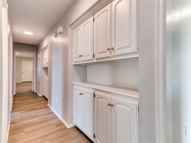 hall with baseboards and light wood-style floors