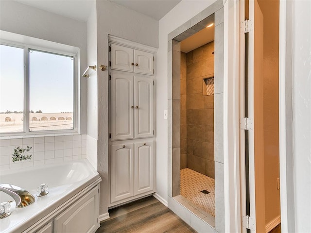 bathroom with a garden tub, wood finished floors, and a tile shower