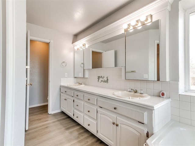 full bathroom with a sink, tasteful backsplash, wood finished floors, and double vanity