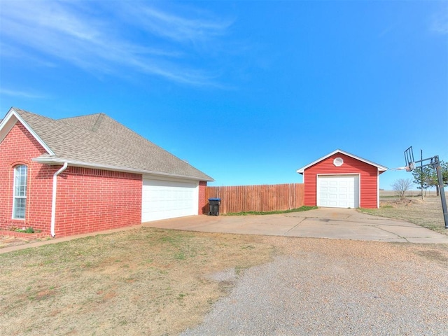 exterior space with an outbuilding, fence, a shingled roof, a garage, and brick siding