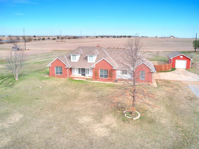 view of front of property featuring a rural view, a detached garage, a front lawn, an outbuilding, and driveway