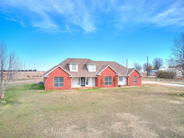 view of front of house featuring a front yard, brick siding, and a shingled roof