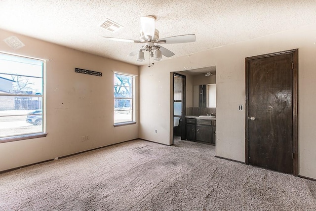 unfurnished bedroom featuring a sink, light colored carpet, visible vents, and a textured ceiling