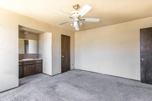 unfurnished bedroom featuring light colored carpet, a textured ceiling, ceiling fan, and a sink