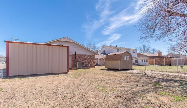 view of yard featuring a storage unit, central air condition unit, an outdoor structure, and fence