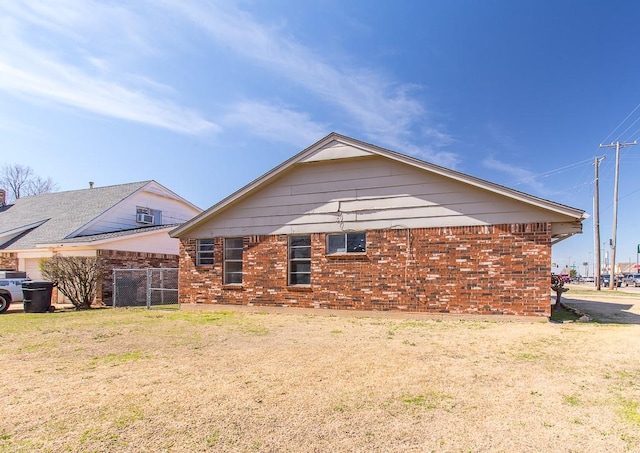 view of side of home with fence, a lawn, and brick siding