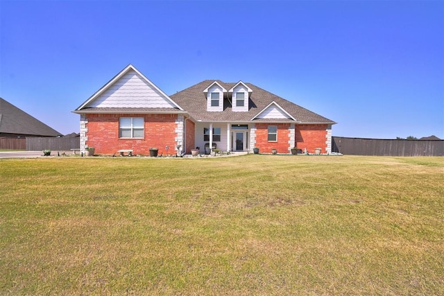 view of front of home with brick siding, a front lawn, and fence