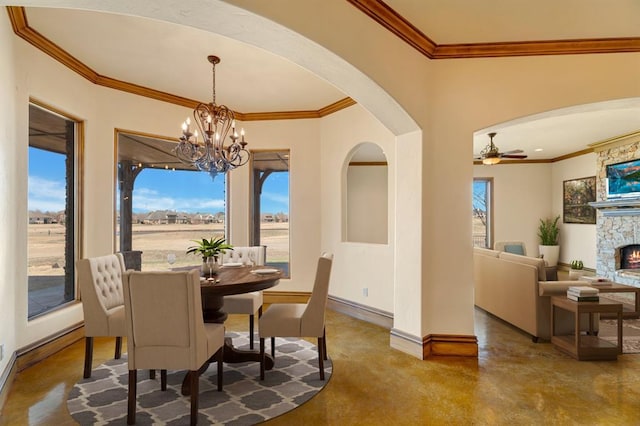 dining room featuring a wealth of natural light, baseboards, arched walkways, and ceiling fan with notable chandelier