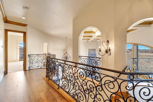 hallway with wood-type flooring, coffered ceiling, beam ceiling, and arched walkways