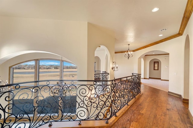 corridor featuring wood finished floors, visible vents, baseboards, recessed lighting, and crown molding