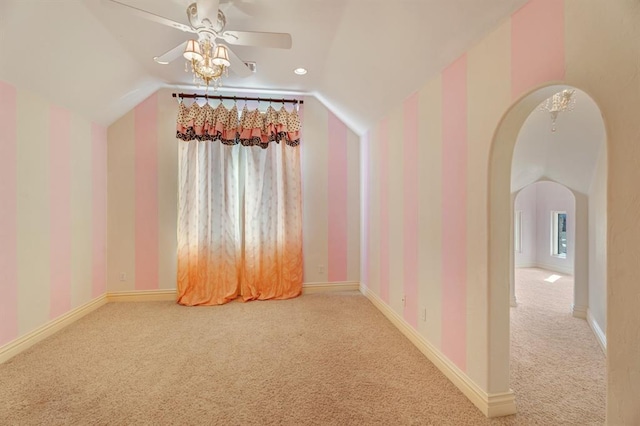 carpeted empty room with arched walkways, ceiling fan, baseboards, and lofted ceiling