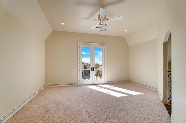 interior space with a ceiling fan, baseboards, carpet floors, arched walkways, and vaulted ceiling