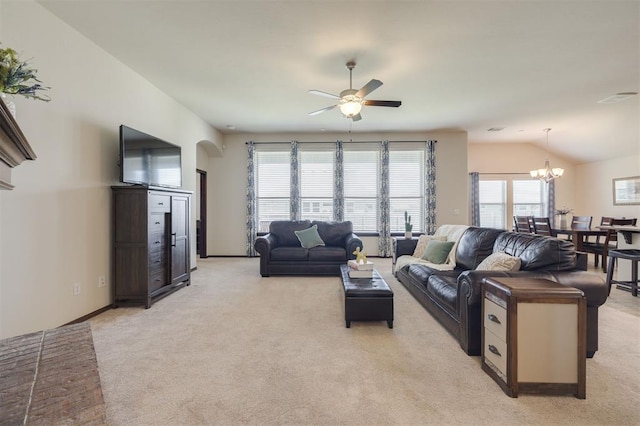 living area with visible vents, vaulted ceiling, light carpet, ceiling fan with notable chandelier, and arched walkways