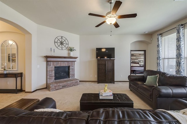 living area featuring a brick fireplace, carpet flooring, a ceiling fan, and baseboards