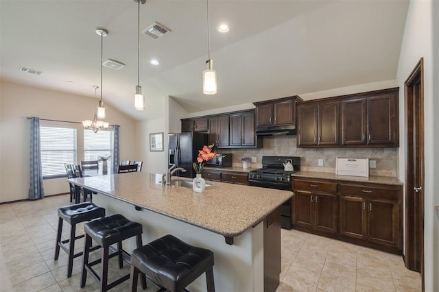 kitchen with visible vents, under cabinet range hood, a breakfast bar, black appliances, and a sink