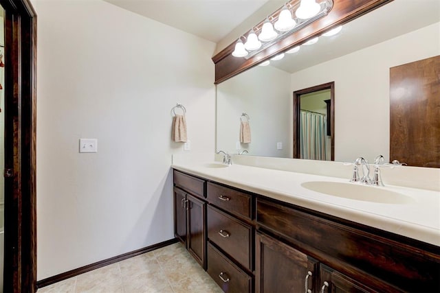 bathroom with double vanity, tile patterned floors, baseboards, and a sink