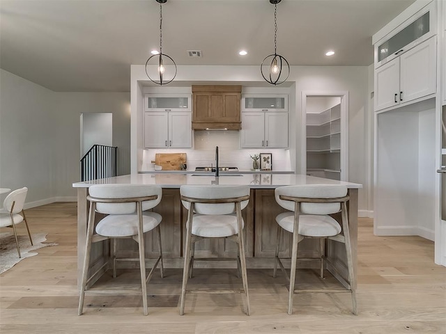 kitchen with decorative backsplash, baseboards, light wood finished floors, and light countertops