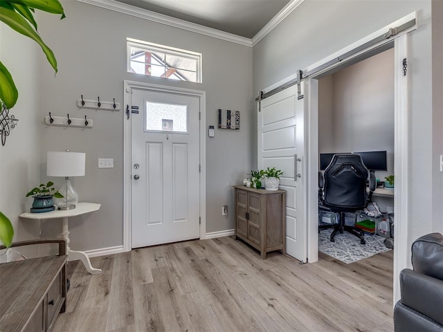 foyer entrance with baseboards, light wood-type flooring, crown molding, and a barn door