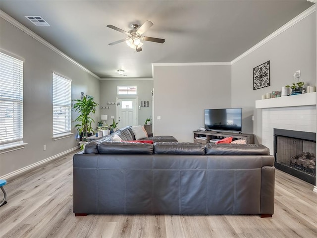 living area with visible vents, crown molding, baseboards, light wood-style floors, and a ceiling fan