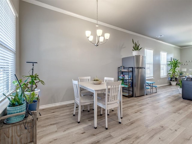 dining room with baseboards, visible vents, light wood-style flooring, ornamental molding, and a notable chandelier