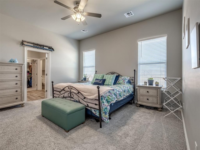 carpeted bedroom with a spacious closet, visible vents, and ceiling fan