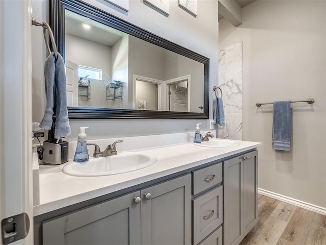 bathroom featuring double vanity, wood finished floors, baseboards, and a sink