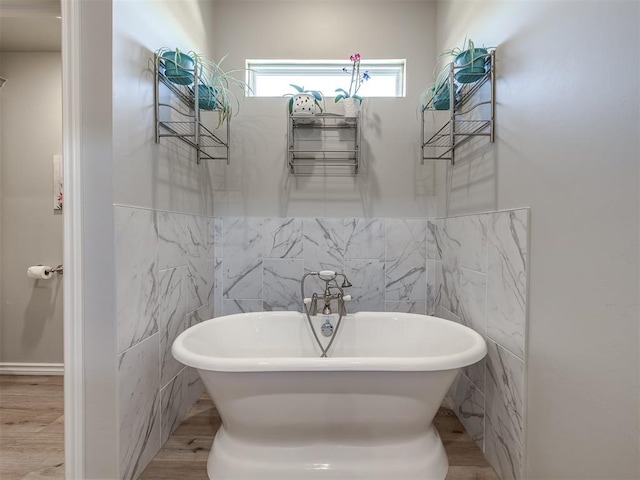 bathroom featuring tile walls and a freestanding bath