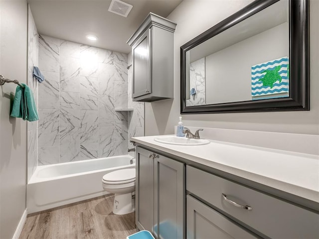 bathroom with vanity, wood finished floors, visible vents, shower / washtub combination, and toilet