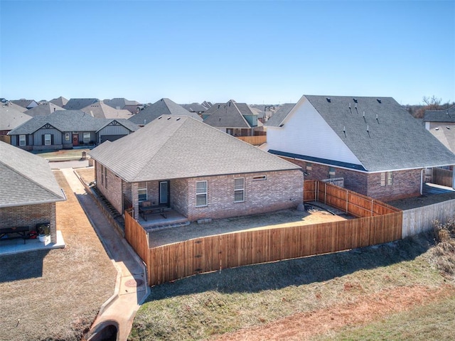 rear view of house featuring a fenced backyard, a residential view, a patio area, and roof with shingles