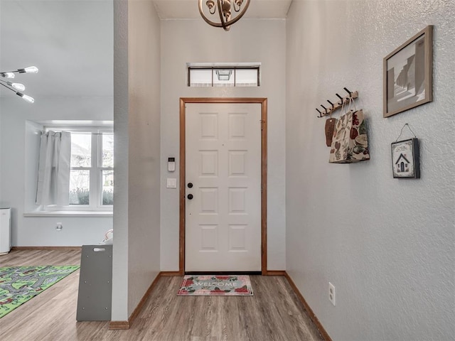 foyer with wood finished floors, baseboards, and a textured wall