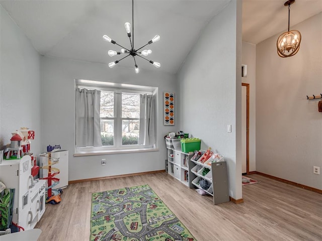 recreation room featuring vaulted ceiling, a notable chandelier, wood finished floors, and baseboards