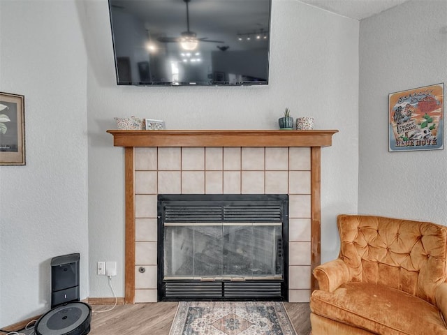 details featuring a tiled fireplace, wood finished floors, and a ceiling fan