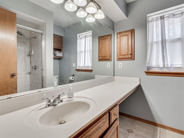 bathroom with vanity, baseboards, tiled shower, tile patterned flooring, and a textured ceiling