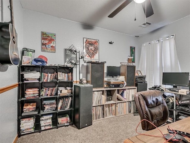 carpeted office with visible vents, ceiling fan, and a textured wall