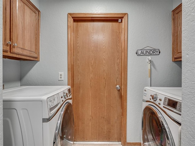 washroom featuring cabinet space, separate washer and dryer, and a textured wall