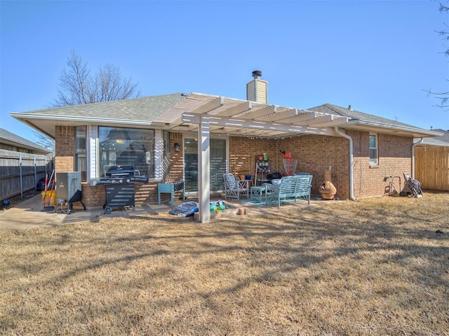 rear view of house featuring fence, a pergola, a chimney, a patio area, and brick siding