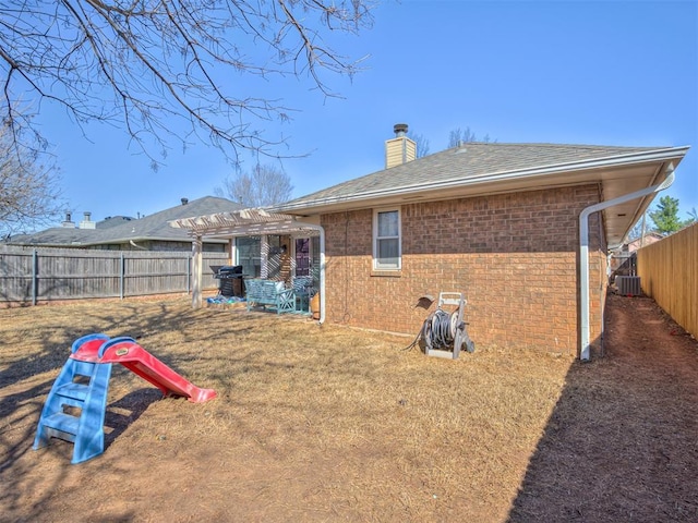 back of property featuring brick siding, a fenced backyard, a chimney, and a pergola