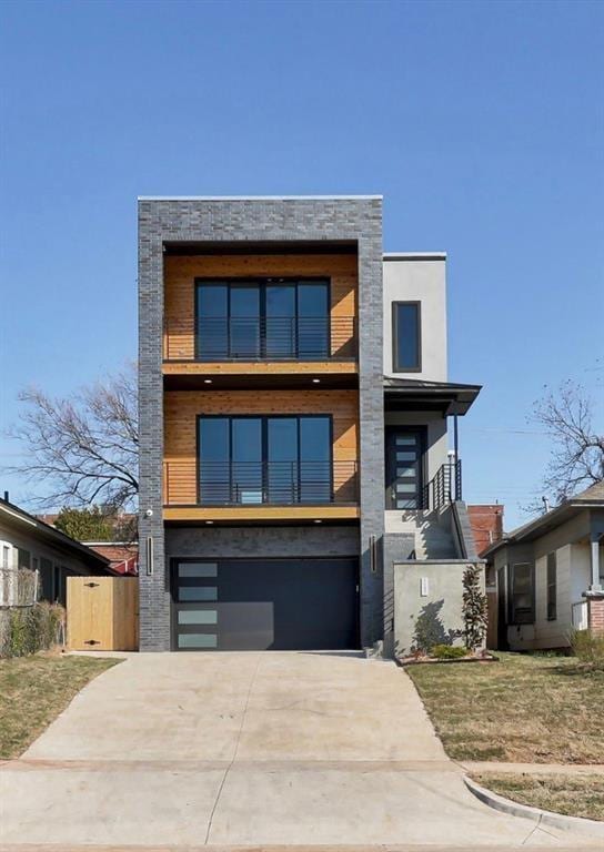 contemporary home featuring stucco siding, an attached garage, concrete driveway, and a balcony