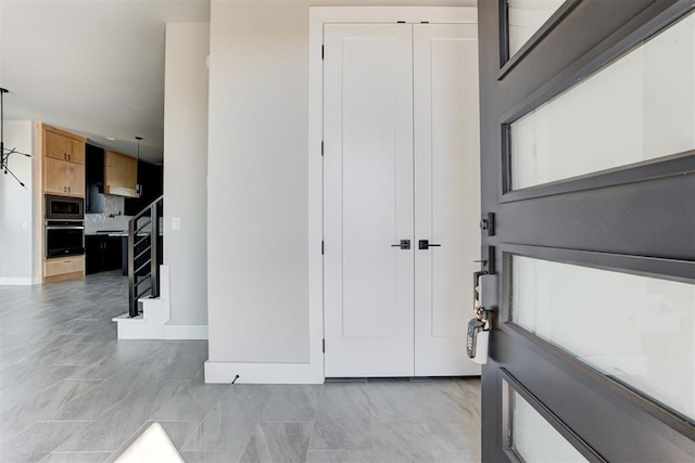 entrance foyer featuring stairway and baseboards