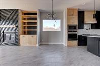 kitchen with oven, hanging light fixtures, light countertops, concrete flooring, and stainless steel microwave