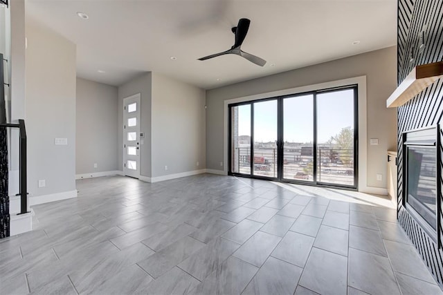 unfurnished living room with baseboards and ceiling fan