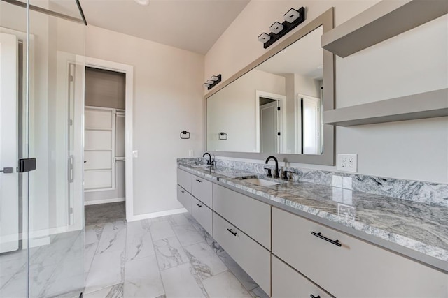 full bathroom with a sink, baseboards, marble finish floor, and double vanity