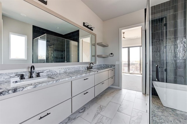 full bath with double vanity, marble finish floor, a shower stall, and a sink