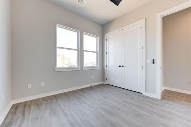 unfurnished bedroom with baseboards, visible vents, a closet, and light wood-type flooring