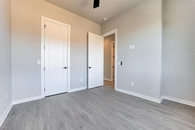 unfurnished bedroom featuring ceiling fan, baseboards, and light wood-style flooring