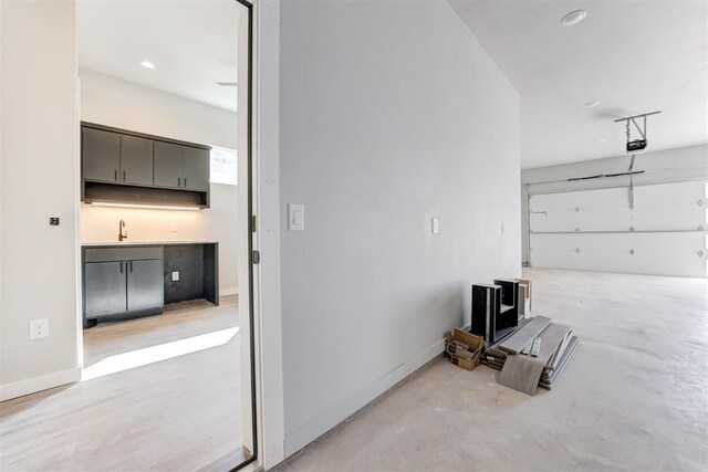 garage featuring a garage door opener, baseboards, and a sink