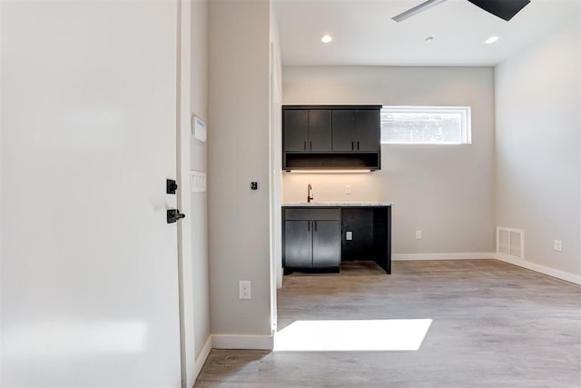 interior space featuring light wood-type flooring, visible vents, baseboards, and indoor wet bar